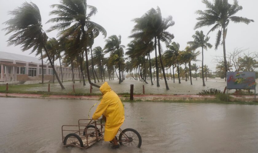 A person rides his bike through a flooded street in the rain in Progreso, Yucatan state, Mexico. Pic: AP