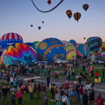 People watch as Meow Wolf's Skyworm hot air balloon takes flight during the Albuquerque International Balloon Fiesta at Balloon Fiesta Park in Albuquerque, N.M., on Tuesday, Oct. 8, 2024. (Chancey Bush/The Albuquerque Journal via AP)