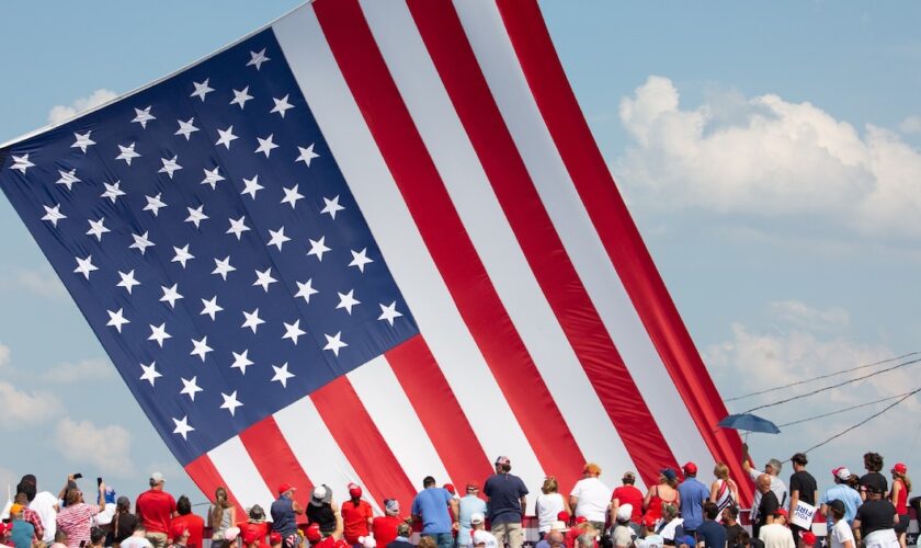 Le drapeau américain flotte au dessus de sympathisants venus assister au meeting où Donald Trump a été la cible de tirs à Butler (nord-est des Etats-Unis), le 13 juillet 2024