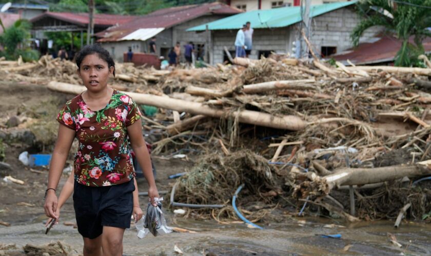 A resident passes by toppled trees after a landslide was triggered by Tropical Storm Trami. Pic: AP Photo/Aaron Favila