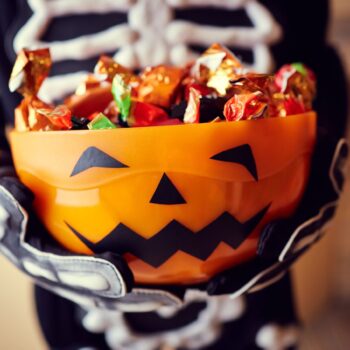 Boy in skeleton costume holding bowl full of candies