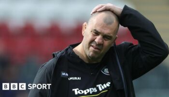 Leicester Tiger's Michael Cheika has his hand on his head while walking off the pitch