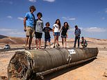 Defiant children play on wrecked rocket in the Israeli desert - as IDF gears up to strike Iran nuclear sites 'within days'