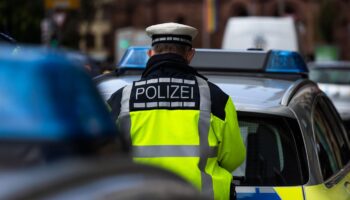 Straftäter gefasst: Ein Polizeibeamter steht zwischen zwei Einsatzfahrzeugen.