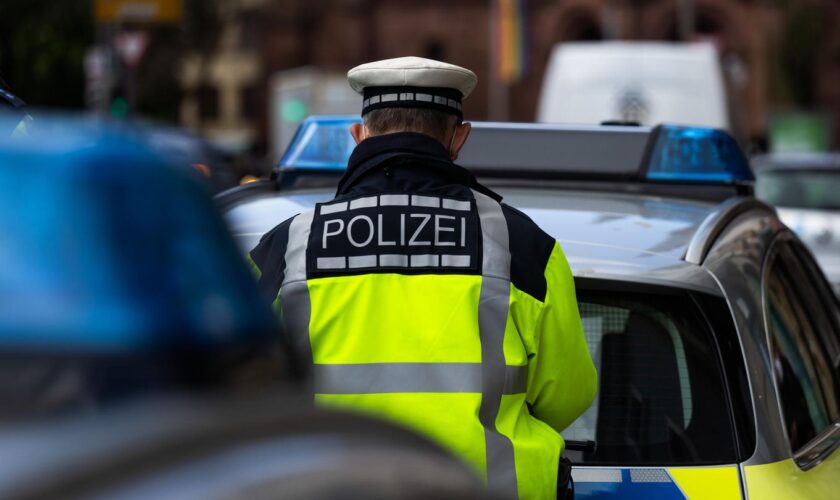 Straftäter gefasst: Ein Polizeibeamter steht zwischen zwei Einsatzfahrzeugen.