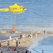 La extinción de un incendio en el Castillo de Santa Bárbara de Alicante con un helicóptero cargando agua en la playa