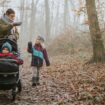 Winterfußsack: Mutter streichelt ihr Kleinkind, das im Buggy in einem Winterfußsack liegt