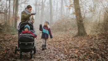 Winterfußsack: Mutter streichelt ihr Kleinkind, das im Buggy in einem Winterfußsack liegt