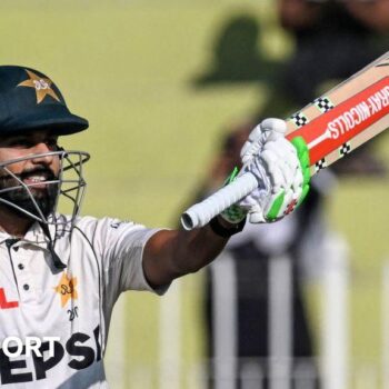 Pakistan batter Saud Shakeel raises his bat to celebrate hitting a century