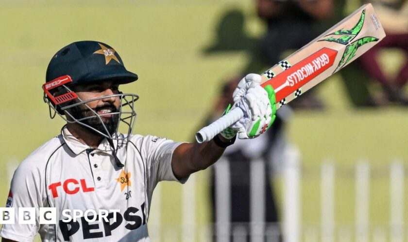 Pakistan batter Saud Shakeel raises his bat to celebrate hitting a century