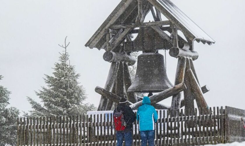 Zwei Wanderer stehen vor der Friedensglocke auf dem Fichtelberg. (Archivbild) Foto: Kristin Schmidt/dpa-Zentralbild/dpa