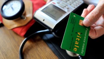 A doctor gives back a French health insurance electronic card (carte vitale) after using it in a connected reader on September 23, 2013 in Godewaersvelde, northern France, during medical exams.  AFP PHOTO / PHILIPPE HUGUEN (Photo by PHILIPPE HUGUEN / AFP)