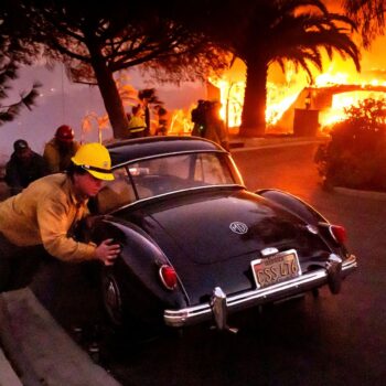 Firefighters and sheriff's deputies push a vintage car away from a burning home as the Mountain Fire burns in Camarillo, Calif., on Wednesday, Nov. 6, 2024. (AP Photo/Noah Berger)