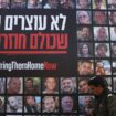 Un homme passe à Jérusalem devant un grand panneau où sont affichés des portraits d'otages israéliens détenus à Gaza, le 18 novembre 2024