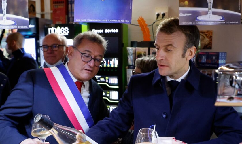 Le président français Emmanuel Macron (à droite) et le maire de Vierzon, Nicolas Sansu (à gauche), boivent un verre de vin dans un café de la ville de Vierzon, le 7 décembre 2021. (Photo de Ludovic MARIN / AFP)