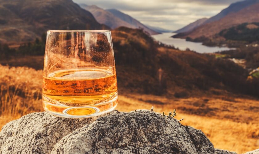 Glass of single malt Scotch Whisky on an old rock above Glenfinnan in the West Highlands of Scotland.