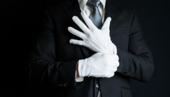 Ein Butler zieht weiße Handschuhe an