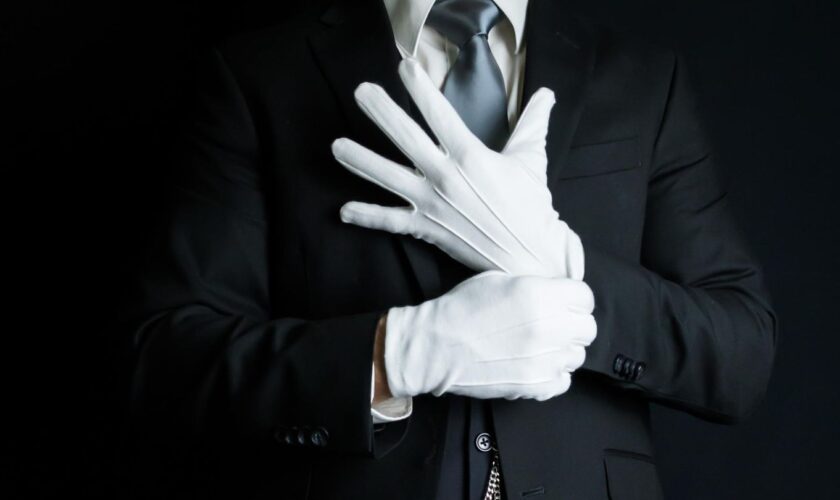 Ein Butler zieht weiße Handschuhe an