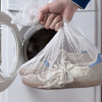 Ein Mann hält Sportschuhe in einem Wäschesack