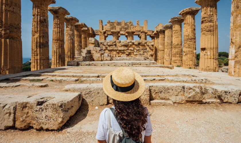 Eine Frau steht vor den antiken Ruinen in Athen.