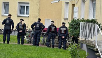 Fünf Polizistinnen und Polizisten stehen vor einem Haus