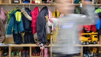 Ein Kind einer Kindergartengruppe läuft an der vollen Garderobe vorbei