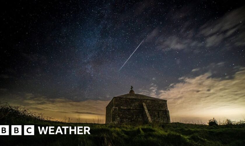 Church building in foreground with a shooting star streaking across the night sky beyond