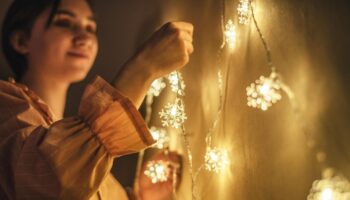 EIne Frau hängt Lichterketten auf