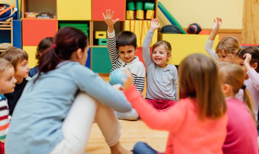 Kinder sitzen in der Kita im Kreis um ihre Erzieherin