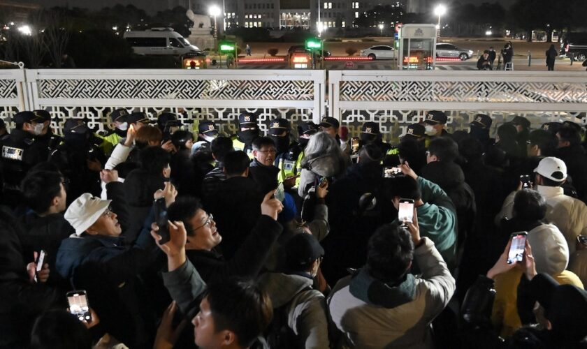 Des gens se rassemblent devant l'Assemblée nationale à Séoul, en Corée du Sud, le 4 décembre 2024, après que le président Yoon Suk Yeol a déclaré la loi martiale