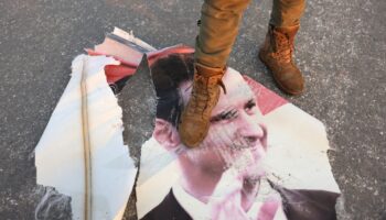 Un rebelle marche sur un portrait déchiré du président syrien Bachar al-Assad à Hama, le 6 décembre 2024