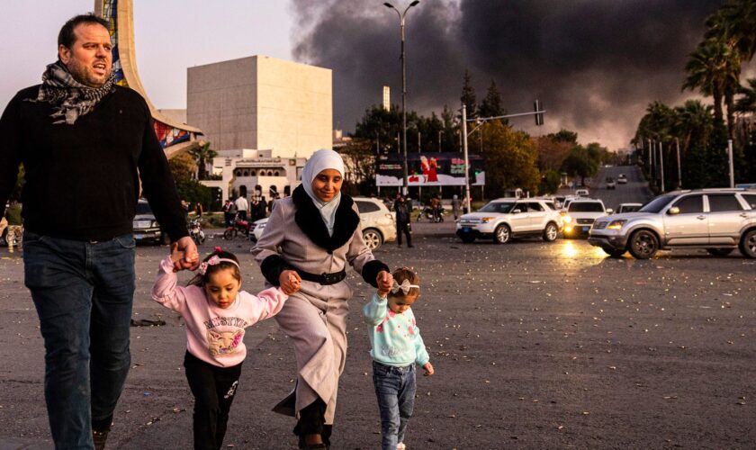 Smoke billows as people arrive to celebrate the fall of the Syrian government, in Damascus, Syria, Sunday, Dec. 8, 2024. (Ugur Yildirim/Dia Photo via AP)