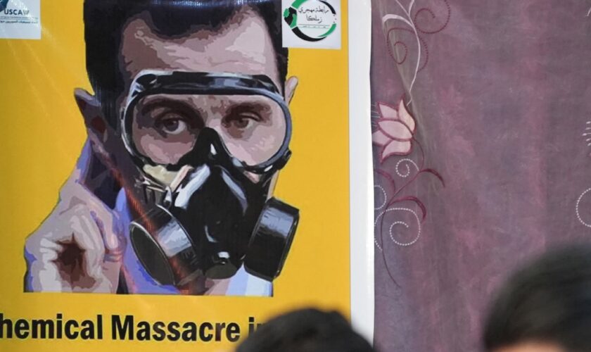 Une affiche représentant le président syrien Bachar al-Assad avec un masque à gaz lors d'une manifestation dans la ville d'Afrin le 20 août 2023, au dixième anniversaire des attaques chimiques qui ont tué plus de 1 400 personnes dans la Ghouta.