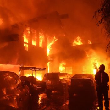 A firefighter sprays water on a home as it burns in the Franklin Fire in Malibu, California., Tuesday, Dec. 10, 2024. (AP Photo/Jae C. Hong)