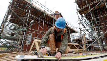 A construction worker uses a tape measure on the construction site of residential buildings in Worcester, Britain December 5, 2024. REUTERS/Temilade Adelaja