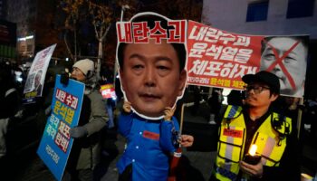 A participant wearing a mask of South Korean President Yoon Suk Yeol attends a rally demanding his impeachment outside the National Assembly in Seoul, South Korea, Sunday, Dec. 8, 2024.The signs read "Arrest Yoon Suk Yeol." (AP Photo/Ahn Young-joon)