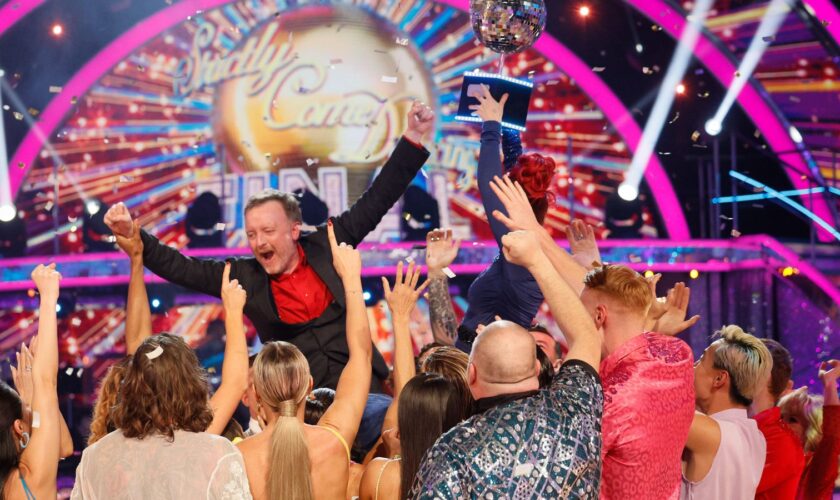 Chris McCausland celebrates his win, as Dianne Buswell holds the glitterball trophy aloft. Pic: PA