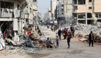 Des personnes marchent devant les décombres de bâtiments effondrés et endommagés dans une rue de la ville de Gaza, le 11 décembre 2024