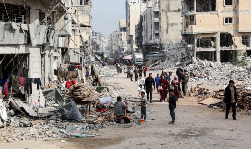 Des personnes marchent devant les décombres de bâtiments effondrés et endommagés dans une rue de la ville de Gaza, le 11 décembre 2024