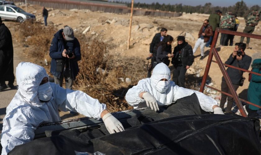 Des membres des Casques blancs syriens se préparent à transporter des corps découverts dans une fosse commune à Damas, le 16 décembre 2024