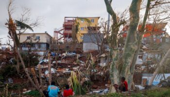 Des habitants assis devant leurs maisons détruites à Mamoudzou après le passage du cyclone Chido à Mayotte, le 17 décembre 2024