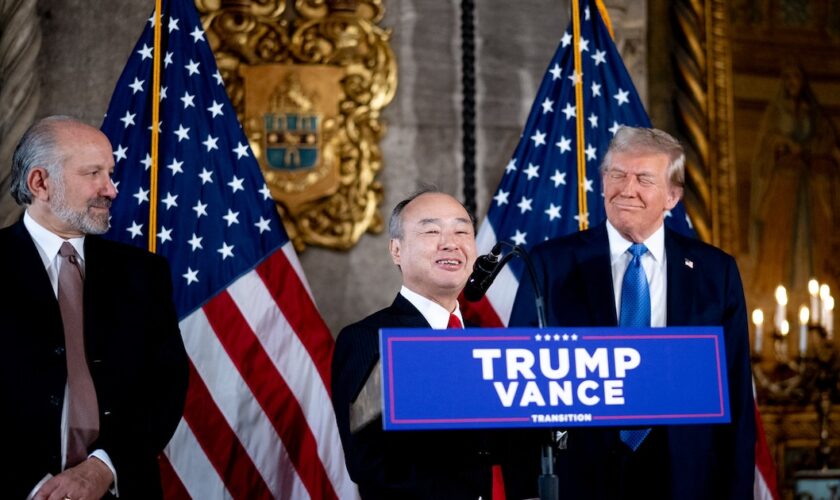 PALM BEACH, FLORIDA - DECEMBER 16: SoftBank CEO Masayoshi Son (C), accompanied by U.S. President-elect Donald Trump (R) and Trump's choice for Secretary of Commerce, Cantor Fitzgerald Chairman and CEO Howard Lutnick (L), speaks at a news conference at Trump's Mar-a-Lago resort on December 16, 2024 in Palm Beach, Florida. In a news conference that went over an hour, Trump announced that SoftBank will invest over $100 billion in projects in the United States including 100,000 artificial intelligence related jobs and then took questions on Syria, Israel, Ukraine, the economy, cabinet picks, and many other topics.   Andrew Harnik/Getty Images/AFP (Photo by Andrew Harnik / GETTY IMAGES NORTH AMERICA / Getty Images via AFP)