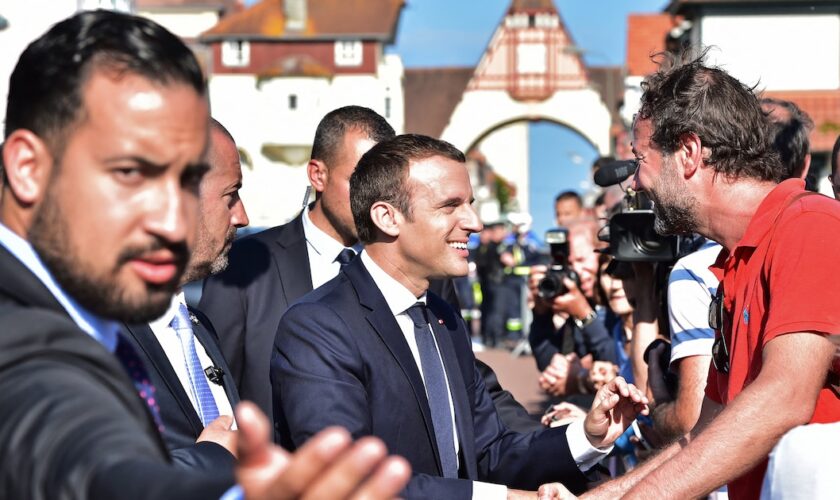 Le président français Emmanuel Macron (C), avec l'officier supérieur de sécurité de l'Élysée Alexandre Benalla (G), serre la main des gens après avoir voté au Touquet, lors du second tour des élections législatives françaises, le 18 juin 2017.