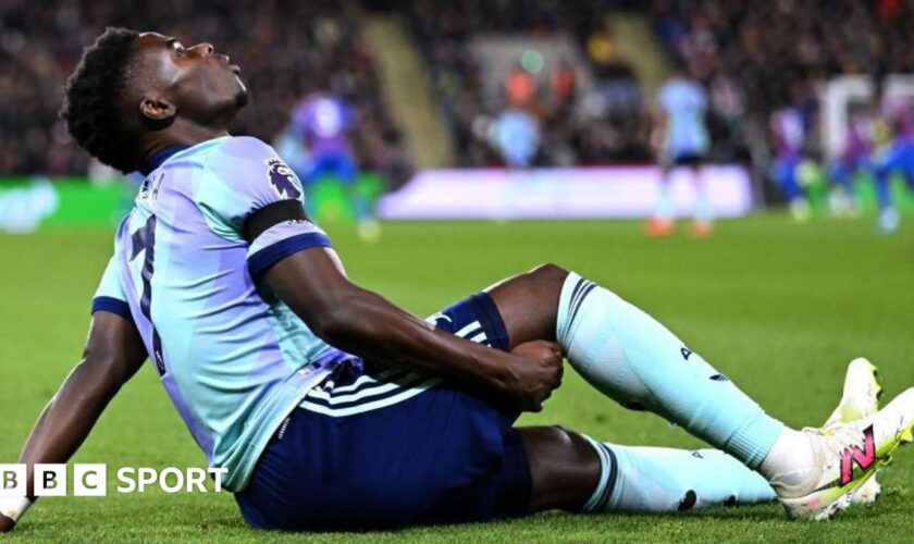 Arsenal's Bukayo Saka holds the back of his leg as he sits on the field after suffering an injury against Crystal Palace