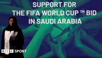 A woman stands in front of a 'support for the Fifa World Cup bid in Saudi Arabia'