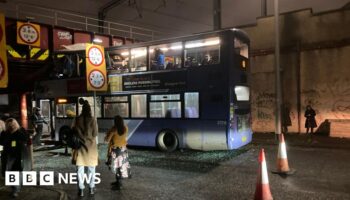 Roof torn off bus after railway bridge crash