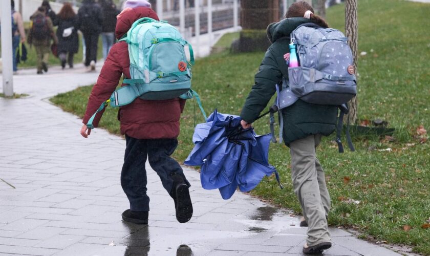 Regen-Wetter: Zwei Kinder mit Schirmen laufen über eine Straße