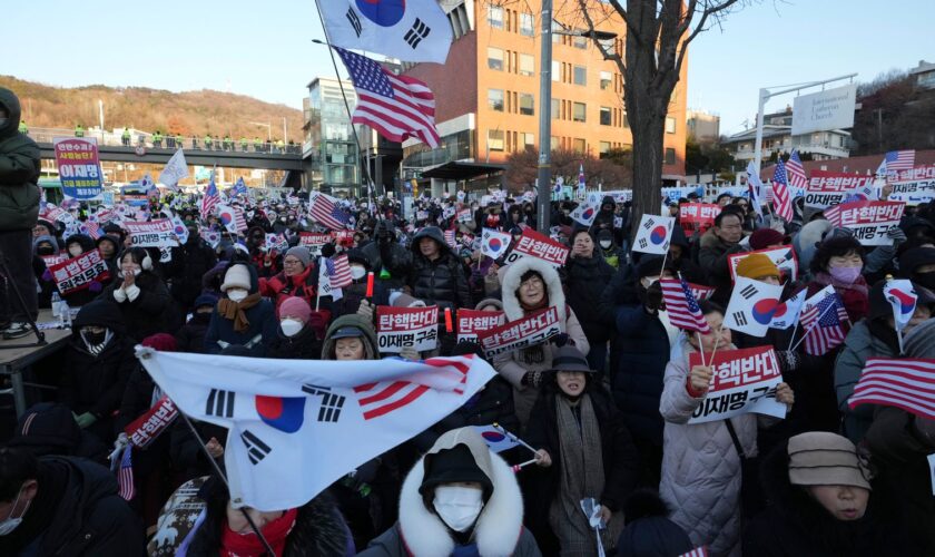 Supporters of impeached South Korean President Yoon Suk Yeol stage a rally to oppose a court having issued a warrant to detain Yoon, as police offices stand guard near the presidential residence in Seoul, South Korea, Friday, Jan. 3, 2025. The letters read "Oppose Impeachment." (AP Photo/Lee Jin-man)