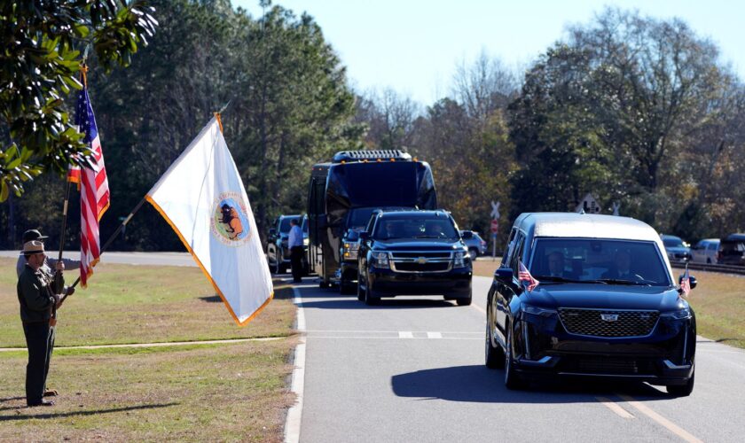 Members of the National Park Service watch as the hearse containing Jimmy Carter's coffin passes through his boyhood Farm in Archery, Georgia. Pic: Reuters