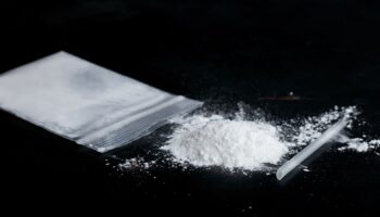 ketamine drugs and plastic straw on bag of white powder on black wood background.Drug epidemic concept.